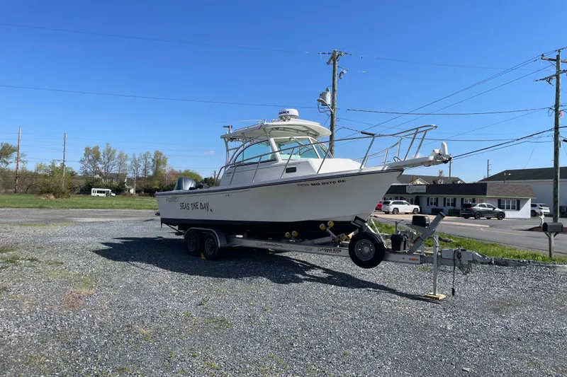 Slide: The Image of 2016 Parker 2510 XL Walkaround boat on trailer in a parking lot under clear blue sky. - 1