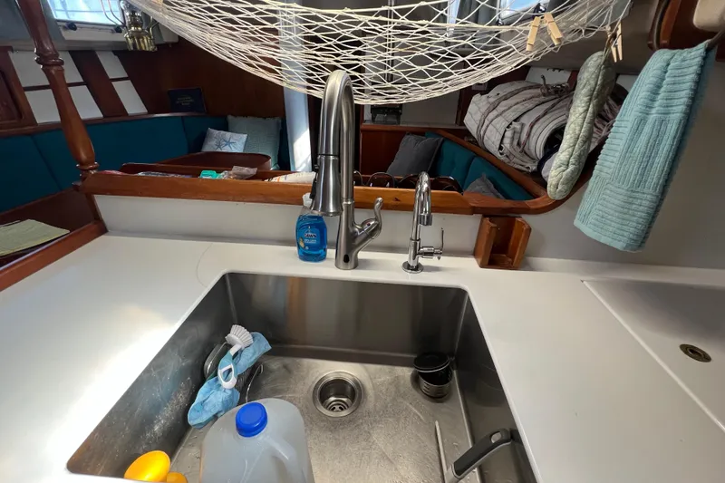 Slide: The Image of Galley sink area in a 1983 Durbeck 50 sailboat, featuring modern fixtures and cozy seating. - 14