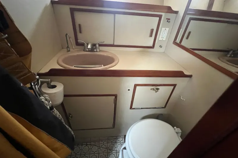Slide: The Image of Compact bathroom in a 1983 Durbeck 50 yacht with sink, toilet, and storage cabinets. - 20