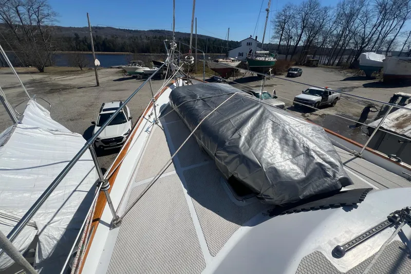 Slide: The Image of Deck view of a 1983 Durbeck 50 sailboat, covered and docked near a serene lake. - 36