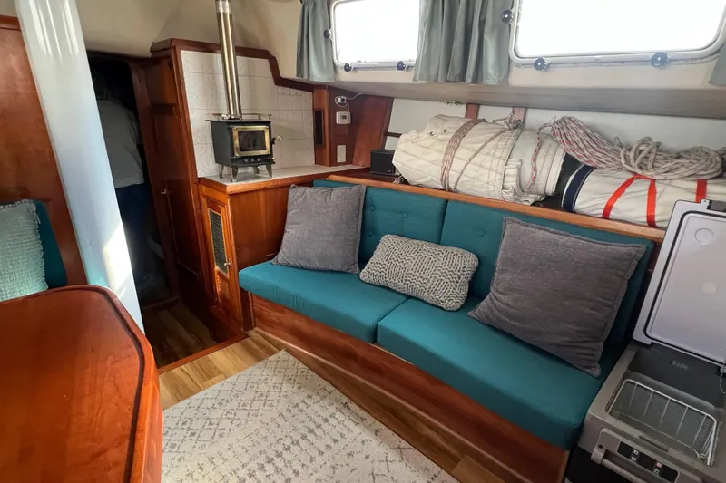 Slide: The Image of Cozy interior of 1983 Durbeck 50 sailboat with teal seating and wood stove. - 4