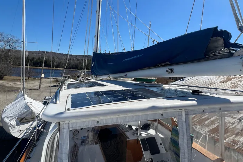 Slide: The Image of 1983 Durbeck 50 sailboat with solar panels on deck, docked near a serene lake. - 40