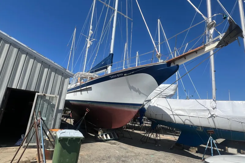 Slide: The Image of 1983 Durbeck 50 sailboat in dry dock, surrounded by other vessels under clear blue sky. - 50