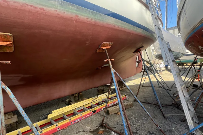Slide: The Image of 1983 Durbeck 50 sailboat hull on stands in a boatyard, undergoing maintenance. - 53