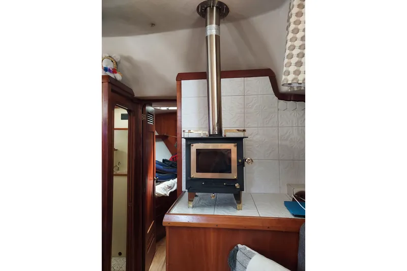 Slide: The Image of Wood stove inside 1983 Durbeck 50 yacht, featuring tiled wall and wooden interior. - 6