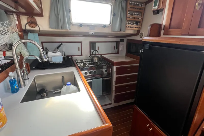 Slide: The Image of Compact kitchen in a 1983 Durbeck 50 yacht with stove, sink, and refrigerator. - 9