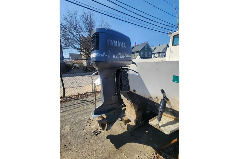 Slide: The Image of Outboard motor on Austin Parker 2520 Cabin boat, 2000 model, parked outdoors. - 10