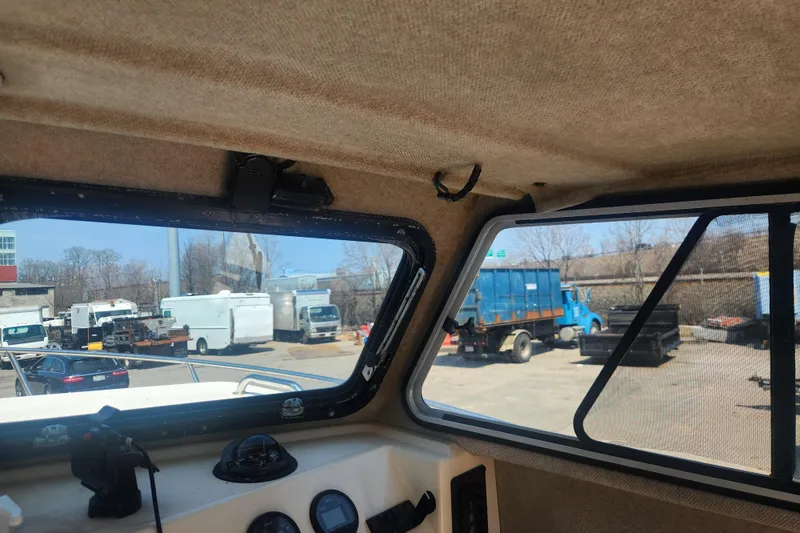 Slide: The Image of Interior view of a 2000 Austin Parker 2520 Cabin boat, overlooking a parking lot. - 12