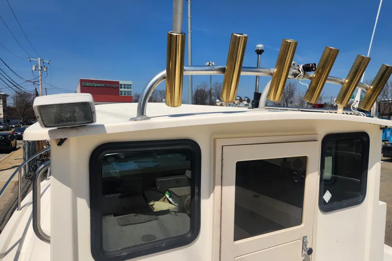 Slide: The Image of Austin Parker 2520 Cabin boat, 2000 model, with rod holders and cabin door, under clear sky. - 4