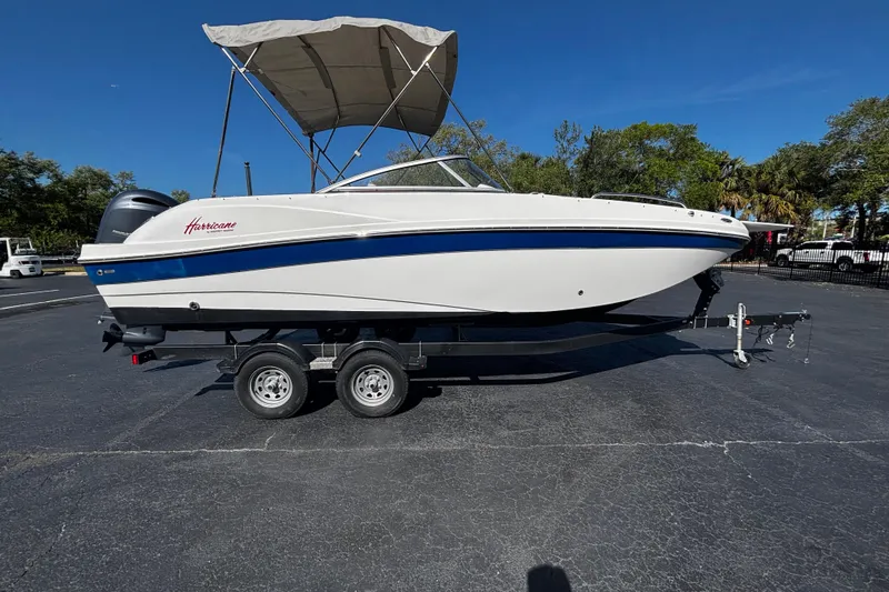 The Image of 2022 Hurricane SunDeck 217 OB boat on trailer, featuring a canopy, parked outdoors. - 1