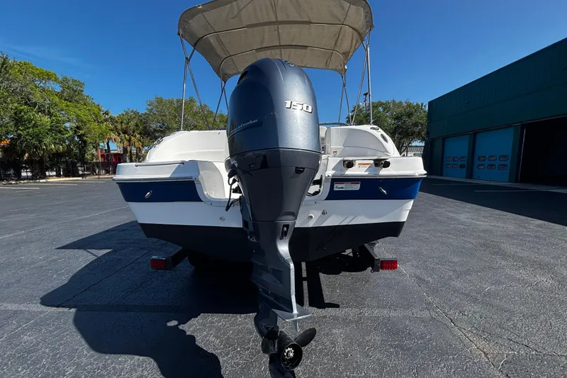 Slide: The Image of 2022 Hurricane SunDeck 217 OB boat with outboard motor, parked outdoors under clear blue sky. - 3