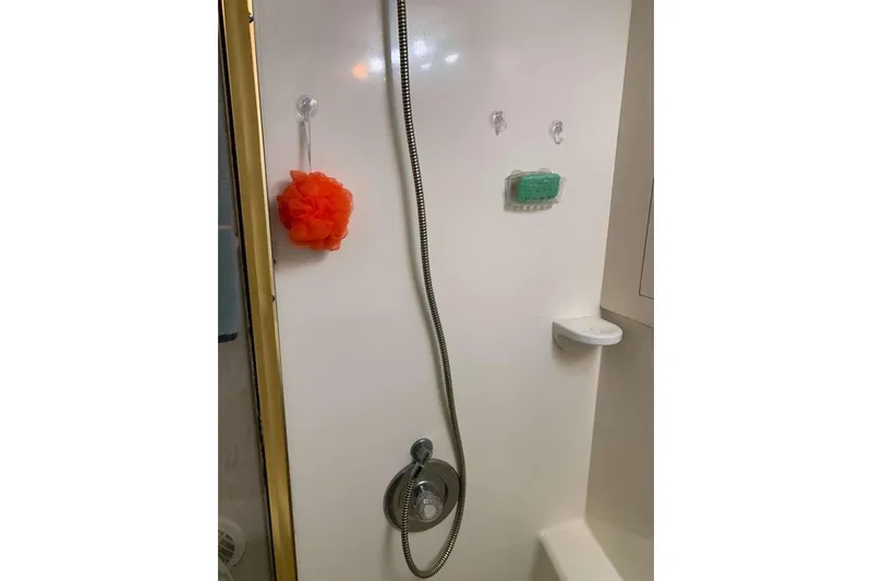 Slide: The Image of Shower area in 1995 Ocean Yachts 42 Super Sport, featuring handheld showerhead and orange bath sponge. - 19