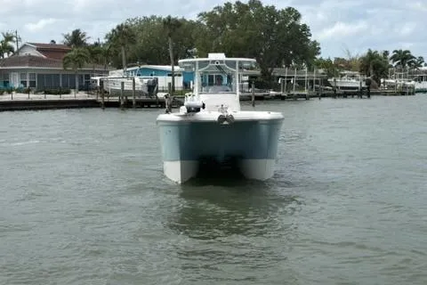 Slide: The Image of 2024 World Cat 295 CC boat cruising in a calm marina with waterfront homes. - 1