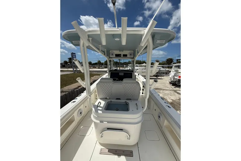 Slide: The Image of 2024 World Cat 295 CC boat interior with helm station and seating under blue sky. - 17