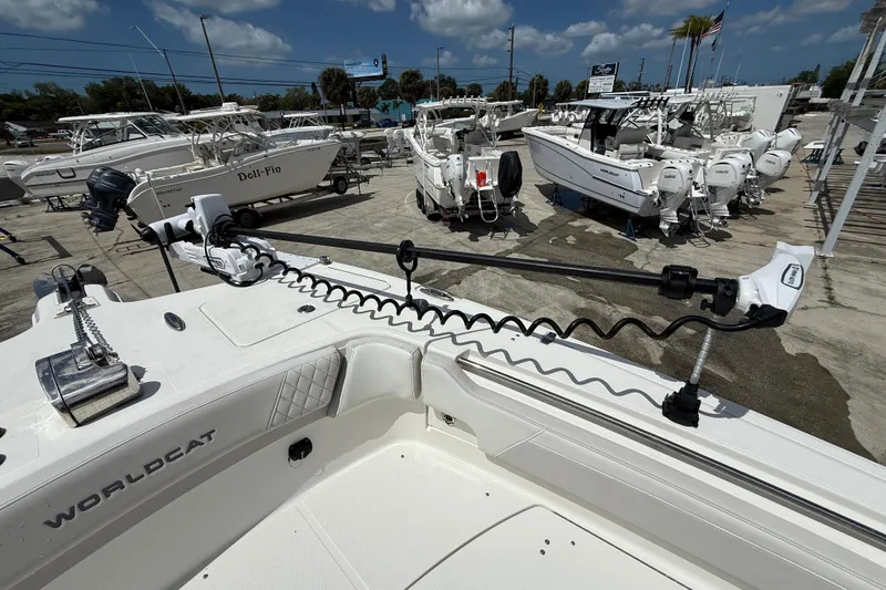 Slide: The Image of 2024 World Cat 295 CC boat with trolling motor, displayed in a marina under a clear sky. - 18