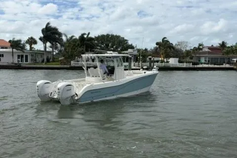 Slide: The Image of 2024 World Cat 295 CC boat cruising on a calm waterway near waterfront homes. - 6