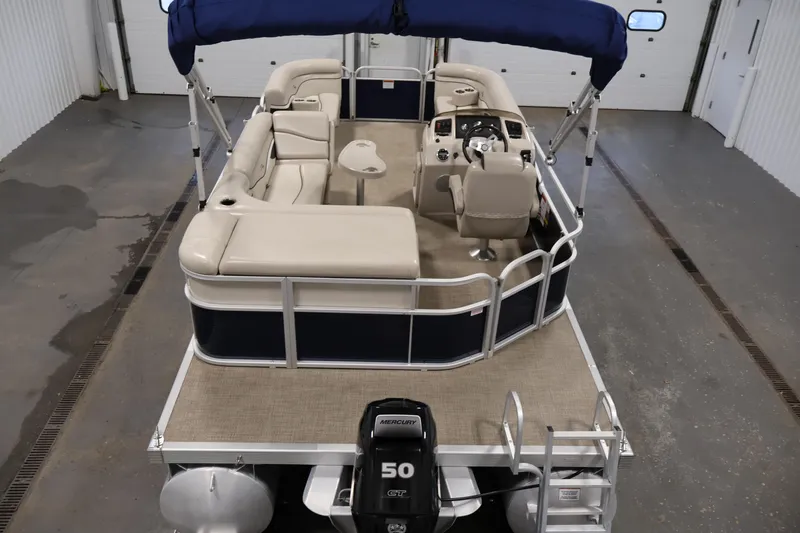 Slide: The Image of 2019 Bennington 20 SL pontoon boat with beige seating and blue canopy in a garage. - 10