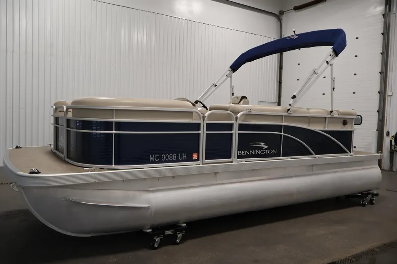 Slide: The Image of 2019 Bennington 20 SL pontoon boat with blue and beige design in indoor storage. - 8