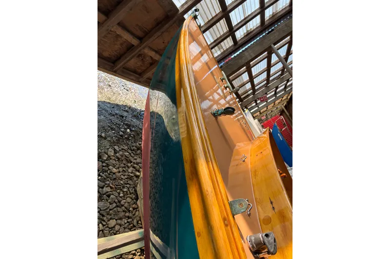 Slide: The Image of 1982 Herreshoff 12.5 footer sailboat under wooden shelter, showcasing polished hull. - 31