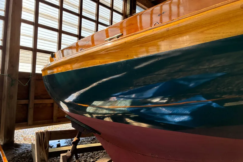 Slide: The Image of 1982 Herreshoff 12.5 footer sailboat in wooden boathouse, showcasing polished hull. - 33