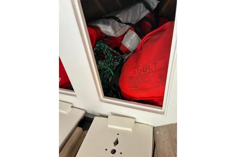 Slide: The Image of Storage compartment with red life jackets and green rope on a 1982 Herreshoff 12.5 footer. - 8
