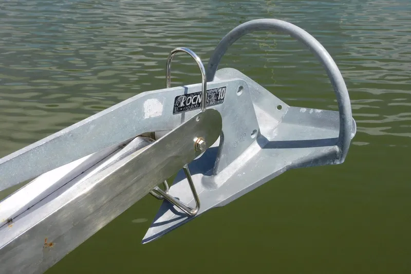 Slide: The Image of Rocna anchor on a 2000 Camano Troll boat, positioned over calm water. - 13