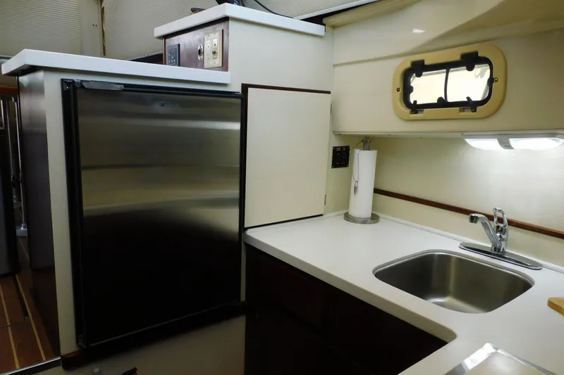 Slide: The Image of Compact kitchen area in a 2000 Camano Troll boat, featuring a sink and refrigerator. - 24