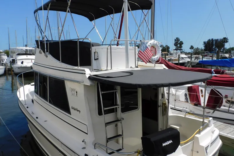 Slide: The Image of 2000 Camano Troll boat docked at marina with American flag and canopy. - 3