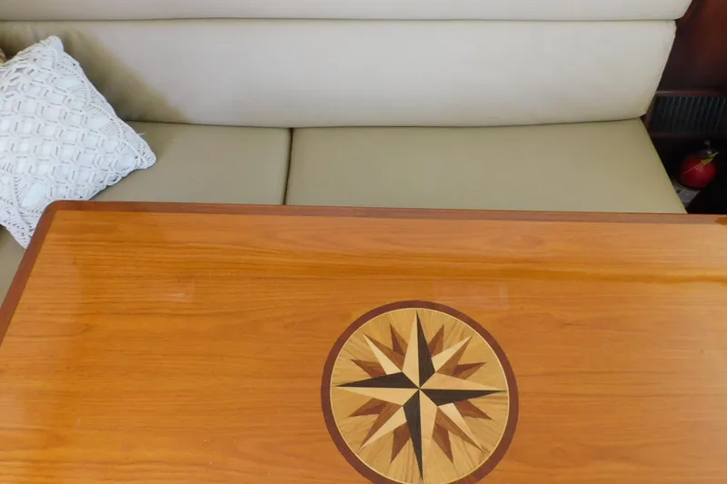Slide: The Image of Wooden table with compass rose design, beige seating, and decorative pillow on Camano Troll 2000. - 43