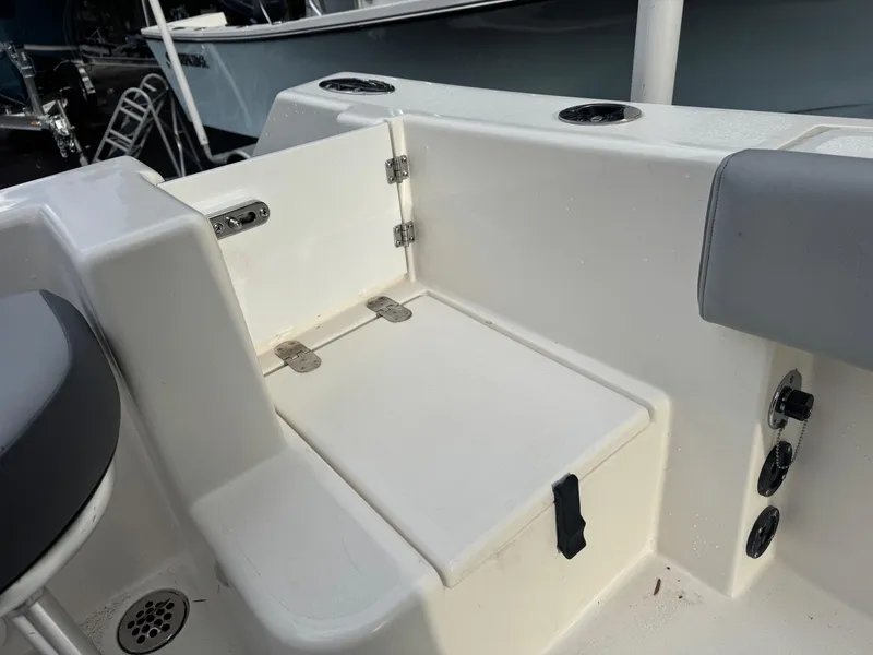 Slide: The Image of Defiance Catalina 240 (2025) boat seating area with storage compartment and cup holders. - 14