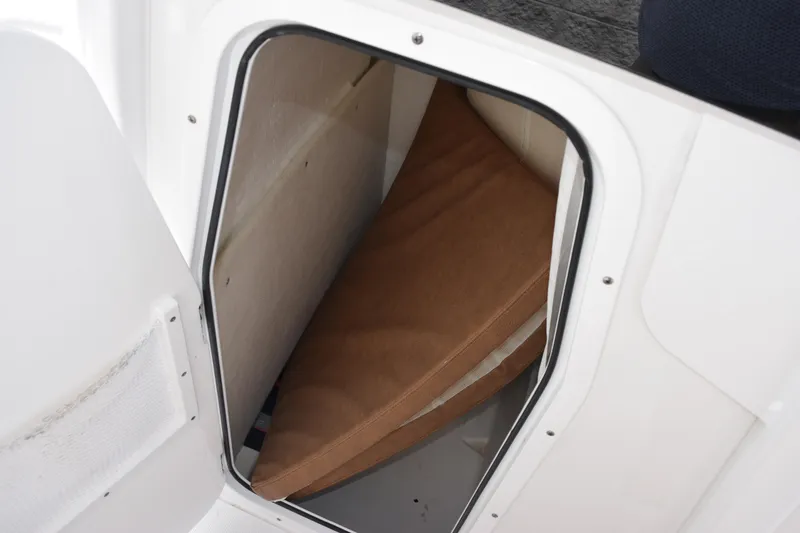 Slide: The Image of 2024 Sea Hunt BX 25 FS storage compartment with brown cushion inside. - 18