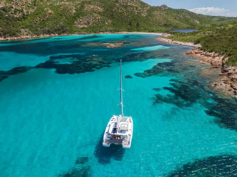 Slide: The Image of Aerial view of Lagoon 38 catamaran in turquoise waters, surrounded by lush green hills. - 67