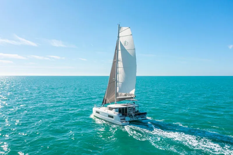 Slide: The Image of 2025 Lagoon 38 catamaran sailing on clear blue ocean under sunny skies. - 79