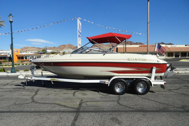 The Image of 2000 Glastron GX 205 boat with red canopy on trailer, parked in urban setting. - 1