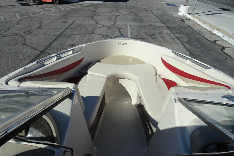 Slide: The Image of 2000 Glastron GX 205 boat interior with red and white seating, parked on pavement. - 12