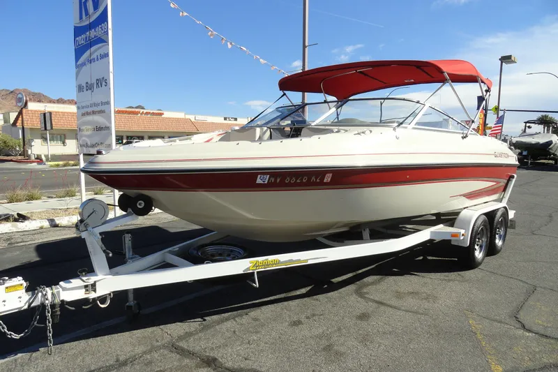 Slide: The Image of 2000 Glastron GX 205 boat with red canopy on trailer in parking lot. - 2
