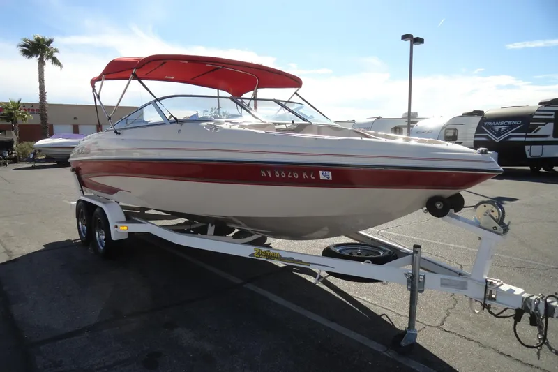Slide: The Image of 2000 Glastron GX 205 boat with red canopy on trailer in parking lot. - 4