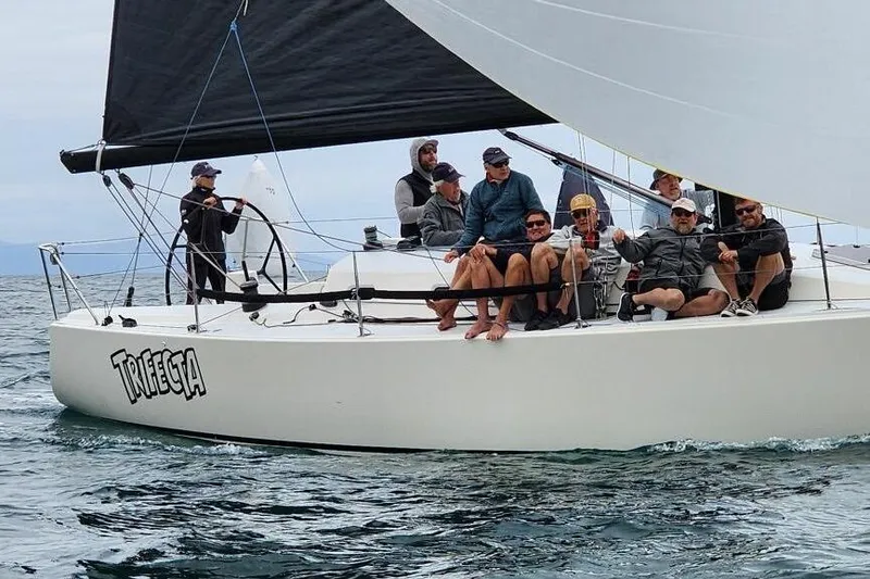 Slide: The Image of Sailors on a 2004 J Boats J/109 yacht named "Trifecta" navigating calm waters. - 11