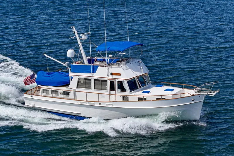Slide: The Image of 1987 Grand Banks 46 Classic yacht cruising on open water with blue canopy. - 13