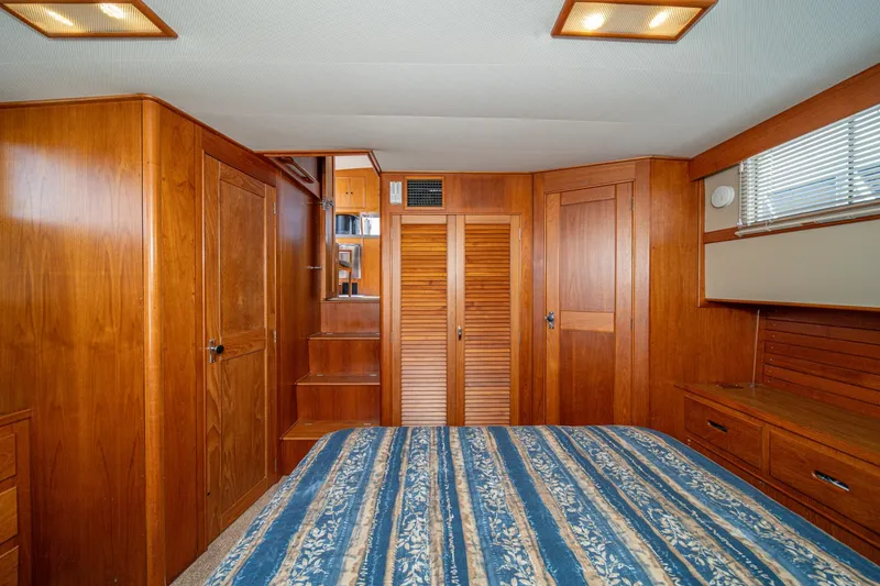 Slide: The Image of Interior of 1987 Grand Banks 46 Classic yacht with wooden cabinetry and striped bedding. - 62