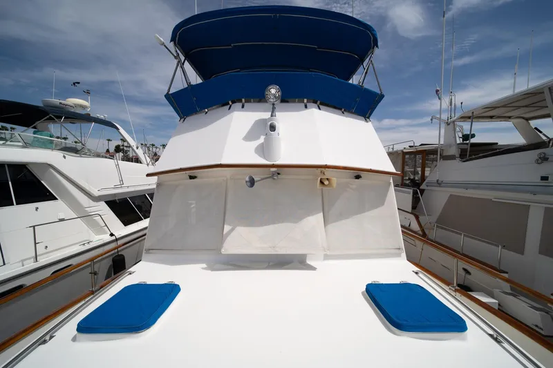 Slide: The Image of 1987 Grand Banks 46 Classic yacht with blue canopy, docked under a clear sky. - 78