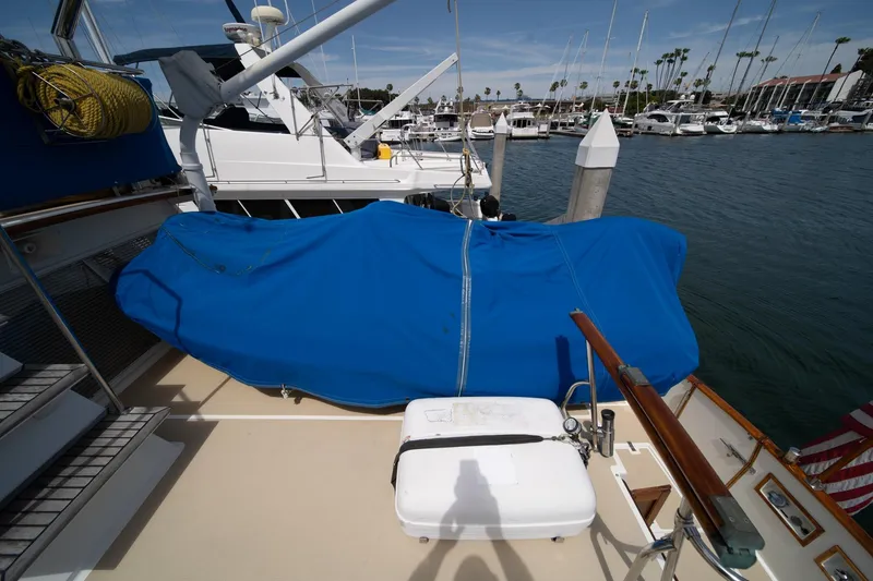 Slide: The Image of 1987 Grand Banks 46 Classic yacht docked, covered with blue tarp, marina background. - 79