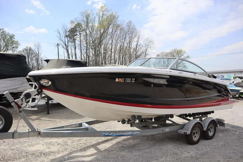 Slide: The Image of 2012 Cobalt A25 boat on trailer, black and white with red trim, parked outdoors. - 1