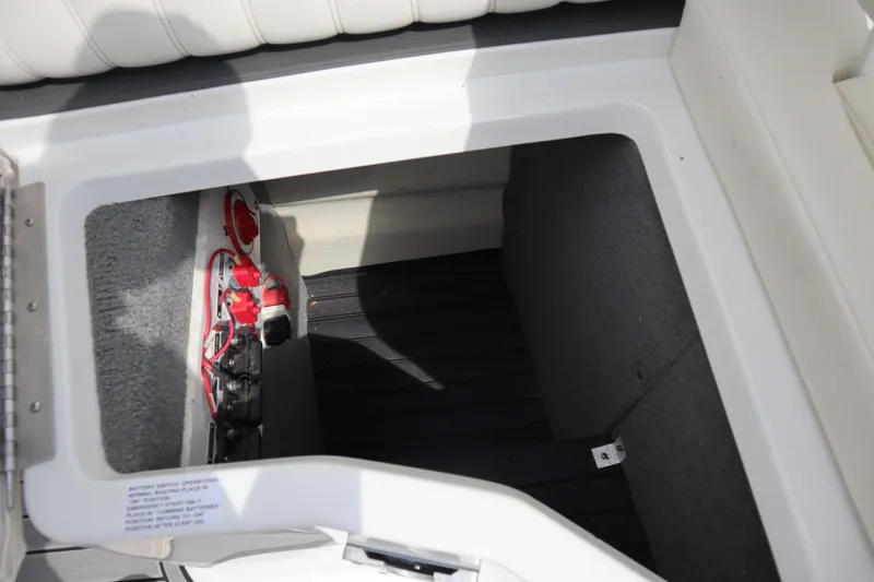 Slide: The Image of Storage compartment in a 2012 Cobalt A25 boat, featuring battery controls and wiring. - 19