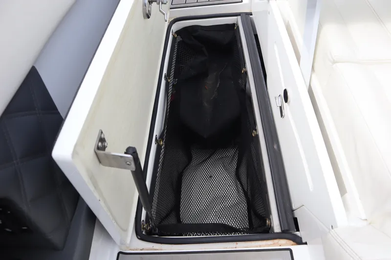 Slide: The Image of Open storage compartment in a 2012 Cobalt A25 boat, featuring a mesh liner. - 25