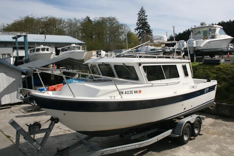 The Image of 2003 SeaSport Explorer 2400 boat on trailer at marina with other boats. - 0