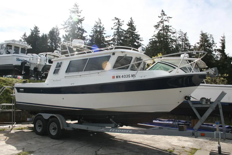 Slide: The Image of 2003 SeaSport Explorer 2400 boat on trailer, surrounded by trees and other boats. - 1