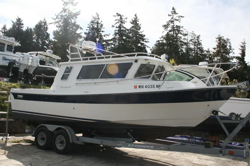 Slide: The Image of 2003 SeaSport Explorer 2400 boat on trailer, surrounded by trees and other boats. - 2