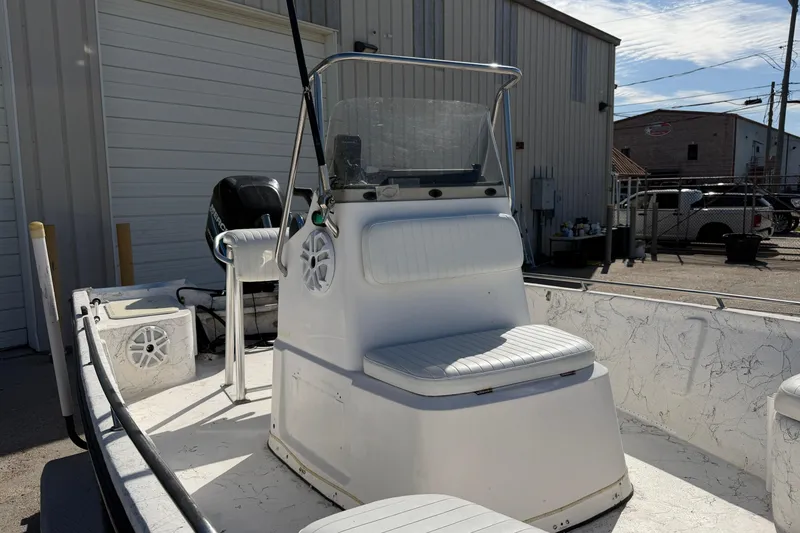 Slide: The Image of 2004 Kenner 1800 VISION boat with seating and console, parked near industrial building. - 11