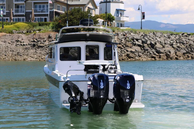 Slide: The Image of SeaSport Kodiak 2600 boat with dual Mercury engines on calm water near rocky shore. - 3